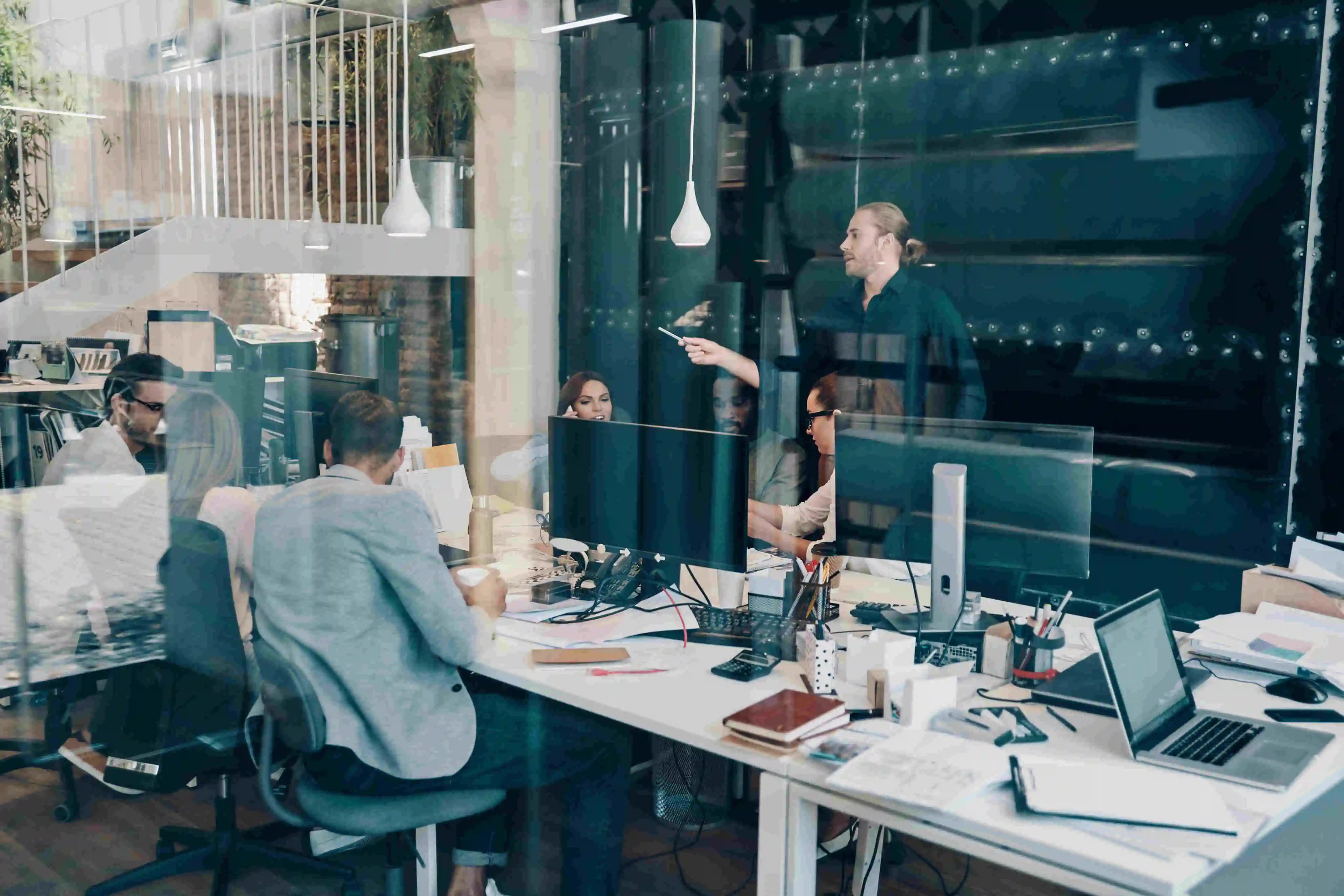 A team of young professionals collaborating on a new project in a modern office sitting in front of computer screens.